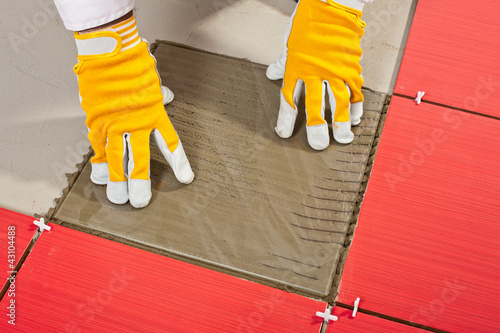 Photo: worker with a glass tile demonstrates how the tile adhesive work worker with a glass tile demonstrates how the tile adhesive work