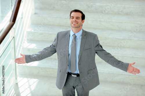 Photo: Satisfied businessman stretching arms out in stairs Satisfied businessman stretching arms out in stairs