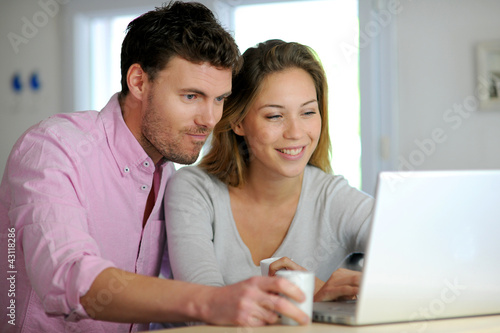 Photo: Happy couple websurfing on laptop computer at home Happy couple websurfing on laptop computer at home