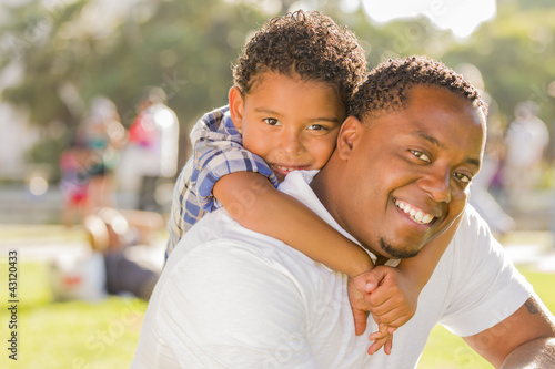 Photo: Mixed Race Father and Son Playing Piggyback in Park Mixed Race Father and Son Playing Piggyback in Park