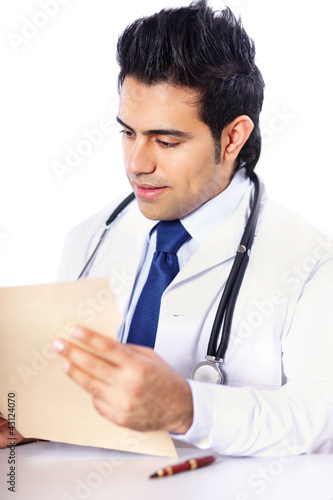 Photo: A male doctor sitting at the desk on white background A male doctor sitting at the desk on white background