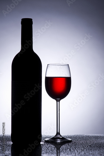 Photo: Rotwein Glas im Gegenlicht mit Weinflasche Rotwein Glas im Gegenlicht mit Weinflasche