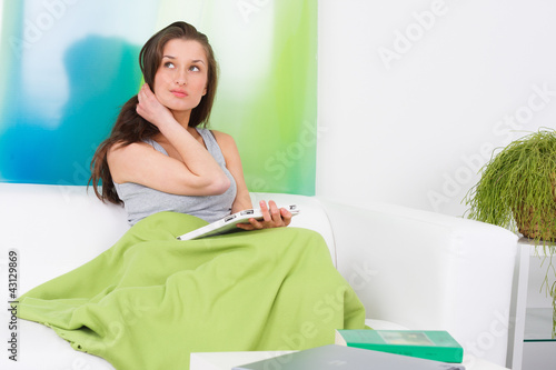 Foto: junge frau sitzt mit touchbook auf dem sofa junge frau sitzt mit touchbook auf dem sofa