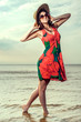 girl in a summer dress and straw hat dancing on the beach