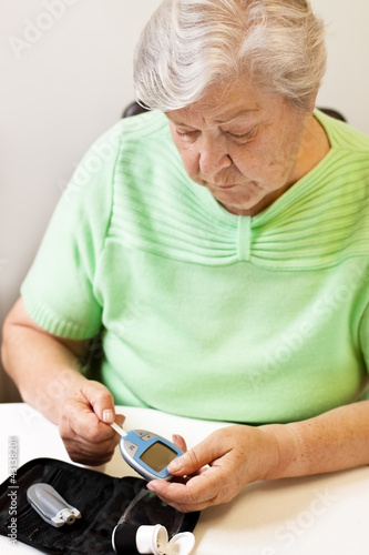 Photo: Seniorin schiebt Teststreifen in das Blutzuckermessgerät Seniorin schiebt Teststreifen in das Blutzuckermessgerät