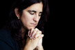 Foto: Sad hispanic woman praying isolated on black Sad hispanic woman praying isolated on black