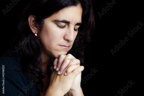 Foto: Sad hispanic woman praying isolated on black Sad hispanic woman praying isolated on black