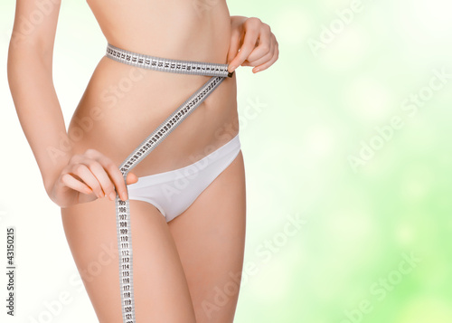 Photo: girl taking measurements of her body, green blurred background girl taking measurements of her body, green blurred background