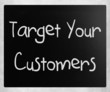 "Target your customers" handwritten with white chalk on a blackb