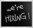 "We are hiring!" handwritten with white chalk on a blackboard