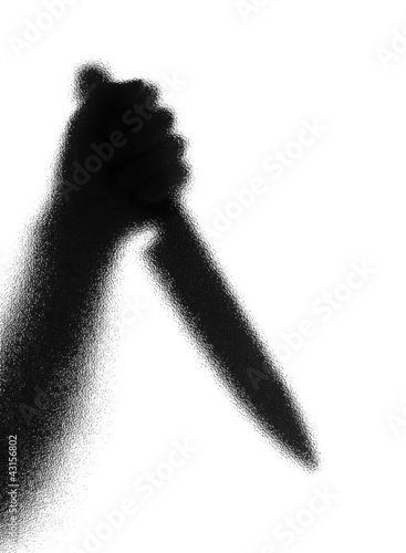 Photo: Knife in a hand. Silhouette. Photographed through the textured g Knife in a hand. Silhouette. Photographed through the textured g