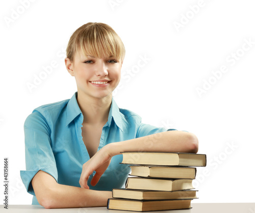 Photo: A smiling woman with books on a desk, isolated on white A smiling woman with books on a desk, isolated on white