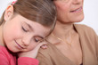 little girl resting on her grandmother's shoulder