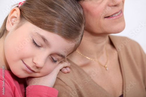Foto: little girl resting on her grandmother's shoulder little girl resting on her grandmother's shoulder