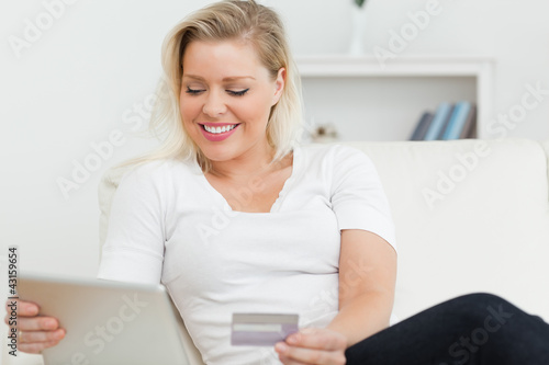 Photo: Casual woman sitting on a sofa using a tablet pc Casual woman sitting on a sofa using a tablet pc