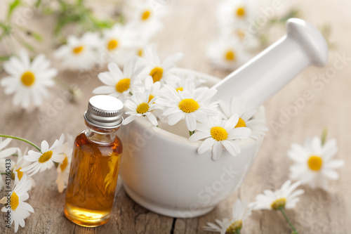 Photo: essential oil and camomile flowers in mortar essential oil and camomile flowers in mortar