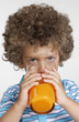 Foto: Niño sujetando un vaso de jugo de naranja,bebiendo jugo. Niño sujetando un vaso de jugo de naranja,bebiendo jugo.
