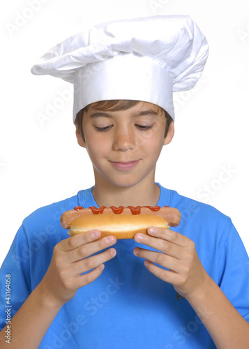 Foto: Niño chef sujetando un hotdog,comiendo perro caliente. Niño chef sujetando un hotdog,comiendo perro caliente.