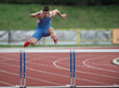 Professional sprinter jumping over a hurdle