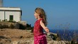 happy little blond girl feeling wind in high cliff  sea