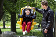 Foto: Father pushing disabled boy in special needs swing Father pushing disabled boy in special needs swing