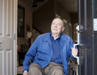 Elderly man in wheelchair at his front door, looking up