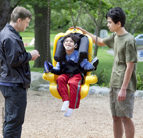Photo: Disabled little boy swinging on special needs swing Disabled little boy swinging on special needs swing