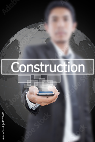 Photo: Businessman holding Construction word on the whiteboard. Businessman holding Construction word on the whiteboard.