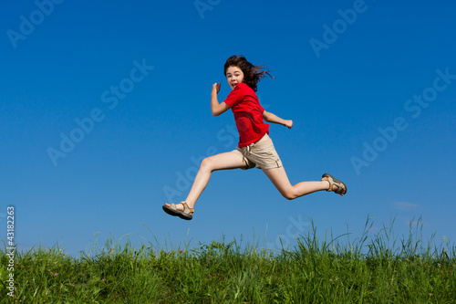 Photo: Girl jumping, running against blue sky Girl jumping, running against blue sky