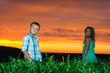 group of happy children playing on meadow, sunset, summertime