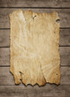 Old paper sheet nailed to a grunge wooden background with copy s