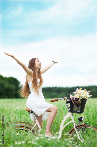 Photo: Woman riding bicycle in wildflower field Woman riding bicycle in wildflower field