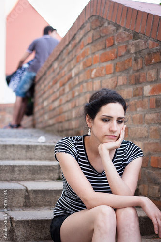 Photo: Depressed young woman sitting in an urban area Depressed young woman sitting in an urban area