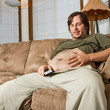 Heavy set man on the couch admiring his stomach