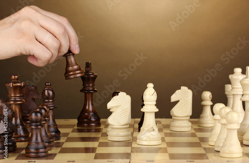 Photo: Chess board with chess pieces on brown background Chess board with chess pieces on brown background
