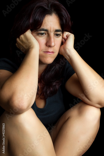 Photo: Depressed and worried hispanic woman isolated on black Depressed and worried hispanic woman isolated on black