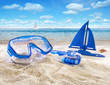 Foto: Goggles and toy sailboat in sand Goggles and toy sailboat in sand