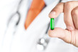 Foto: Close up of male doctor holding green pill Close up of male doctor holding green pill
