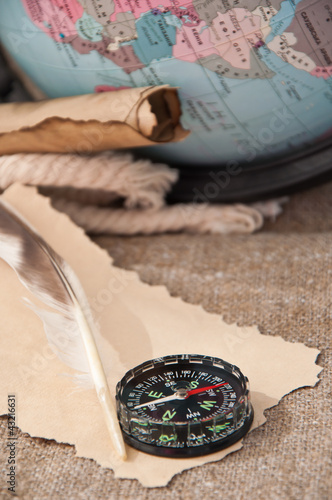 Foto: compass and old papers on the background of the globe compass and old papers on the background of the globe