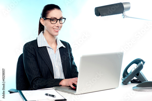 Photo: Smiling female secretary working on laptop Smiling female secretary working on laptop