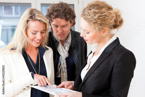 Photo: Young realtor explaining ground plan to couple Young realtor explaining ground plan to couple