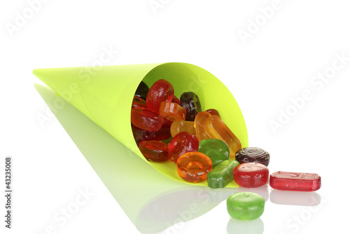 Photo: Tasty colorful candies in bright bag isolated on white Tasty colorful candies in bright bag isolated on white