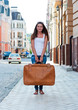 Girl with a big suitcase in the street.