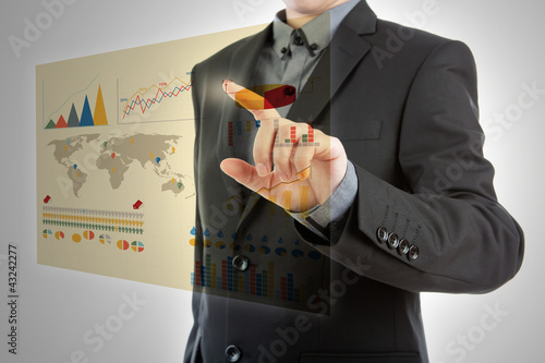 Foto: Business man pressing high tech type of modern graph on a virtua Business man pressing high tech type of modern graph on a virtua