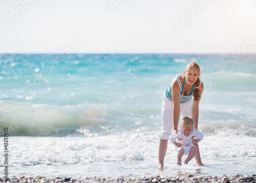Photo: Mother and baby playing with sea waves Mother and baby playing with sea waves