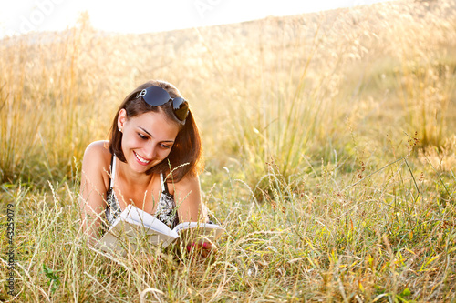 Photo: Woman lies on grass and reads book Woman lies on grass and reads book