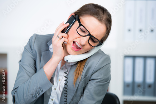 Foto: geschäftsfrau führt zwei telefonate gleichzeitig geschäftsfrau führt zwei telefonate gleichzeitig