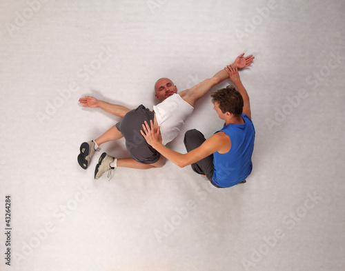 Foto: muscular man stretching with personal trainer in studio muscular man stretching with personal trainer in studio