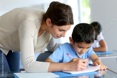 Foto: Teacher helping young boy with writing lesson Teacher helping young boy with writing lesson