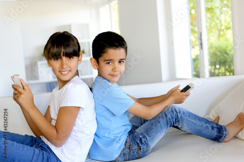 Photo: Kids playing at home with smartphones Kids playing at home with smartphones